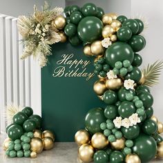 a green and gold balloon arch with flowers