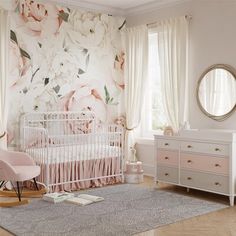 a baby's room with floral wallpaper and pink crib, dressers, and mirror