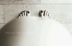 a person's feet with black nail polish on top of a white wall and wood floor