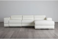 a white leather couch sitting on top of a hard wood floor next to a wall