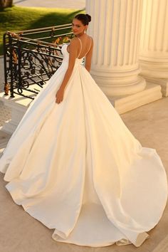 a woman in a white wedding dress standing next to a pillar with columns behind her