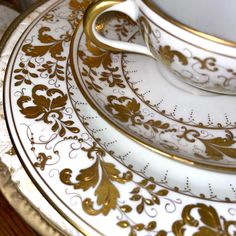 the gold and white plates are stacked on top of each other with matching saucers