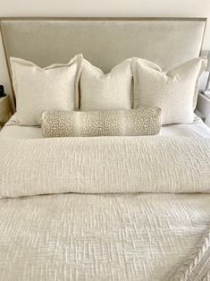 a bed with white linens and pillows on it