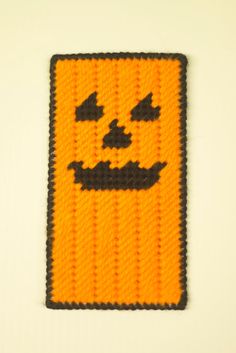 an orange and black knitted patch with a smiling face on it's side