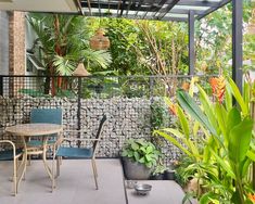 an outdoor patio with tables and chairs next to some tropical plants on the side walk