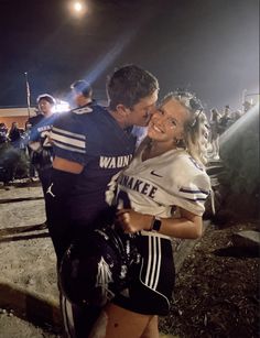 a man and woman embracing each other in front of an audience at a football game