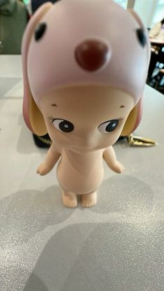 a small toy dog with a pink hat on top of it's head sitting on a table