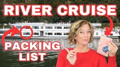 a woman in red shirt holding up a cell phone next to a river cruise boat