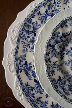 three blue and white plates sitting on top of a wooden table