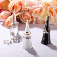 three rings are sitting on top of two small black and white cone shaped vases