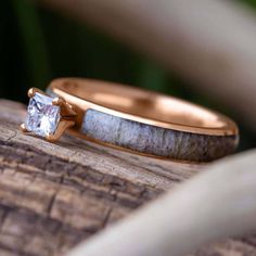 two yellow gold wedding bands with a white diamond in the center on top of a piece of wood