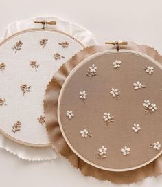 two embroidery hoops with white flowers on them