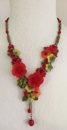 You'll be a pretty girl in this gorgeous piece of jewelry. Handbeaded with hand painted resin flowers and glass beads. This piece pops with bright red and is softened by the complimentary green and yellow flowers that surround it. The beaded flowers are mixed together with a gold toned chain which gives this necklace a decidedly vintage feeling. Finished beautifully with a single drop in the center. Such a pretty piece to add to your wardrobe. This is a quality piece of jewelry that will last a Red Flower Necklace, Shrink Plastic Jewelry, Vintage Feeling, Flower Necklaces, Girl Necklace, Sweet Earrings, Painted Resin, Boho Choker, Shrink Plastic