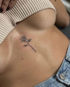 a woman's stomach with a rose tattoo on her left side ribcage