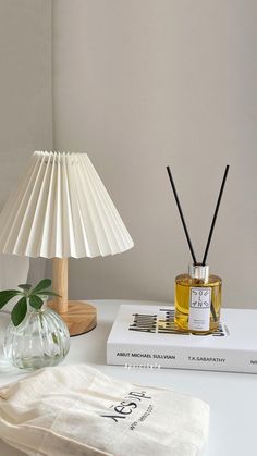 a white table topped with a lamp next to a book