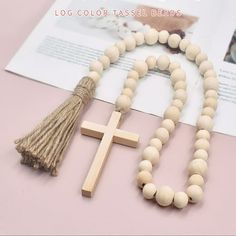 a wooden cross and tassel beads on a pink surface with a book in the background