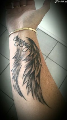 a person's arm with a tattoo on it that reads, angel wings and the word