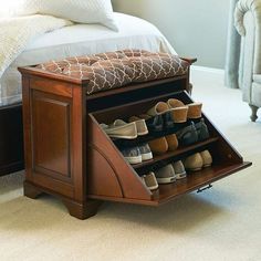 a bed room with a neatly made bed and a shoe rack in the middle of it