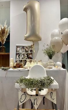 a table topped with white balloons and greenery