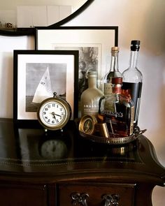 there is a clock, liquor bottles and other items on the table next to it