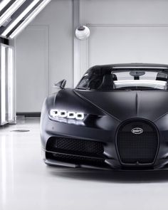 the bugatti supercar is parked in an empty garage with its hood up