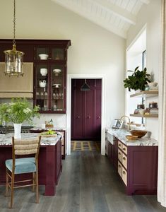 a kitchen with wood flooring and purple cabinetry in the center, along with marble counter tops