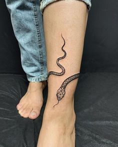 a woman's foot with a snake tattoo on the left side of her leg