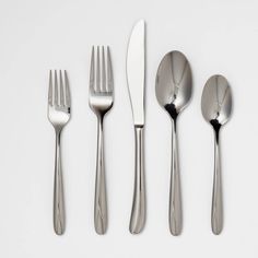 four forks, two knives and three spoons on a white table top with one fork in the middle