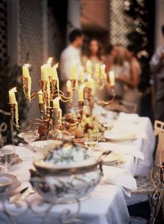 a table with many plates and candles on it