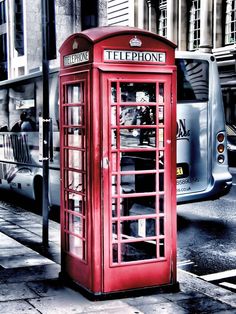 a red telephone booth sitting on the side of a street