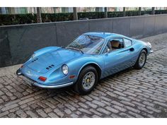 a blue sports car parked in front of a building on a cobblestone street