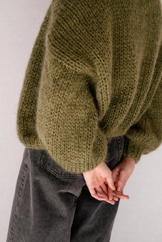 a person wearing a green sweater and jeans