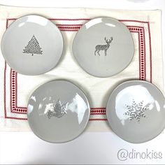 three white plates with designs on them sitting on a red and white place mat next to each other