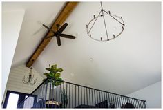 a ceiling fan and chandelier hanging from the ceiling in a room with white walls