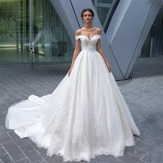 a woman in a white wedding dress standing on a brick floor next to a building