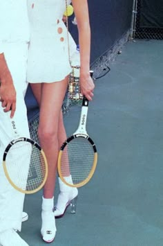 a man and woman standing next to each other holding tennis racquets