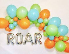 the word roar spelled out with balloons in front of a white wall and two orange, green, and blue balloons