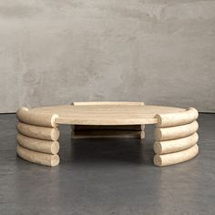 a coffee table made out of logs on a concrete floor in front of a wall