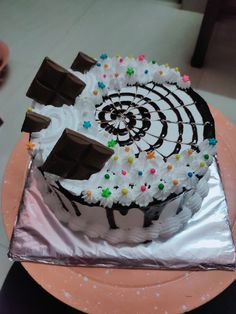 a cake with white frosting, chocolate and sprinkles sitting on top of a pink plate