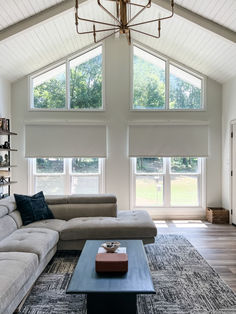 a living room with two couches and a coffee table in front of three windows