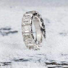 a white gold ring with baguetts of diamonds on top of snow covered ground