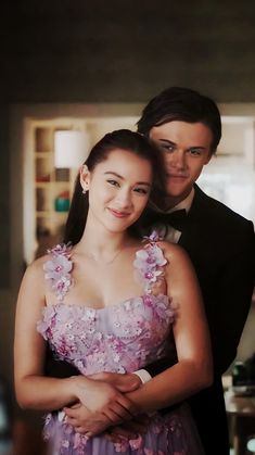 two people standing next to each other in formal wear and tuxedo with flowers on them