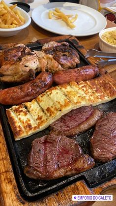 steak and other meats on a grill with french fries