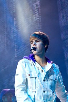 a boy in white jacket and blue jeans on stage