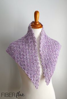 a white mannequin wearing a purple knitted shawl on top of a dummy