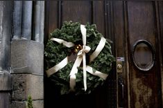 a wreath with white ribbon hanging on a door