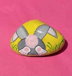 a painted rock sitting on top of a pink surface