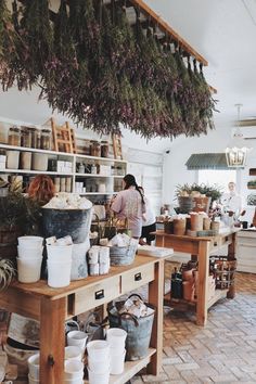 a woman standing in a room filled with lots of potted plants and buckets