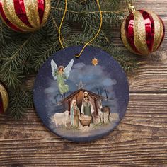 a christmas ornament with an angel and three sheeps in front of it