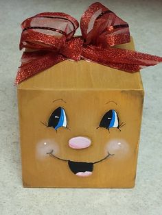 a wooden box with a face painted on it and a red ribbon tied around the top